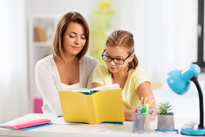 A tutor supporting a young pupil with their reading
